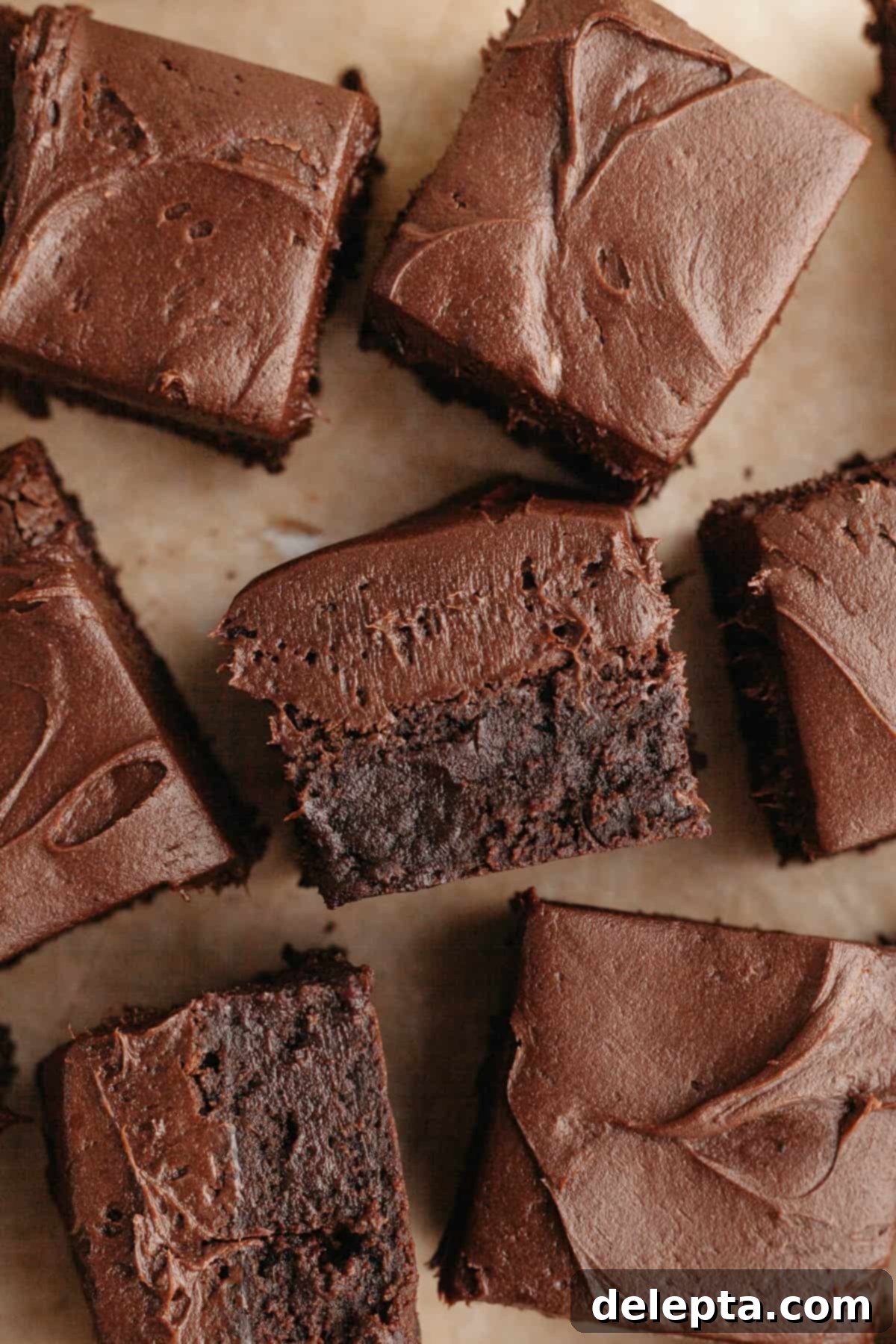Rich Chocolate Brownies with Tangy Cream Cheese Frosting 11 Close-up of frosted chocolate brownies on parchment paper, showing the rich texture.
