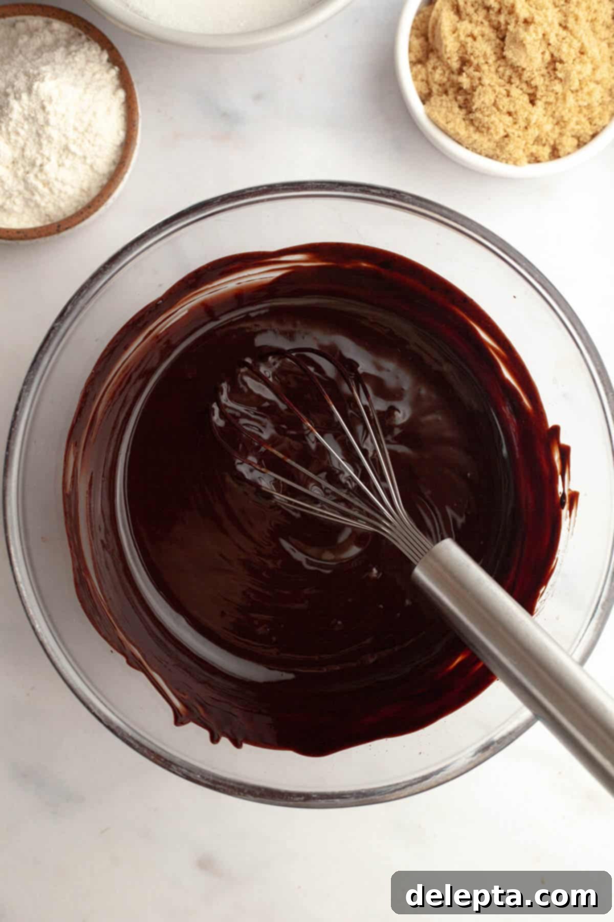 Rich Chocolate Brownies with Tangy Cream Cheese Frosting 4 Melted chocolate and butter in a bowl with a whisk, starting the brownie batter.