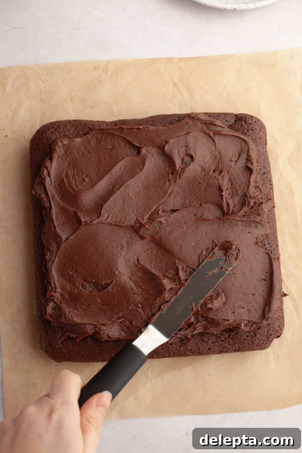 Rich Chocolate Brownies with Tangy Cream Cheese Frosting 9 Cooled brownies being frosted with a generous layer of chocolate cream cheese frosting.