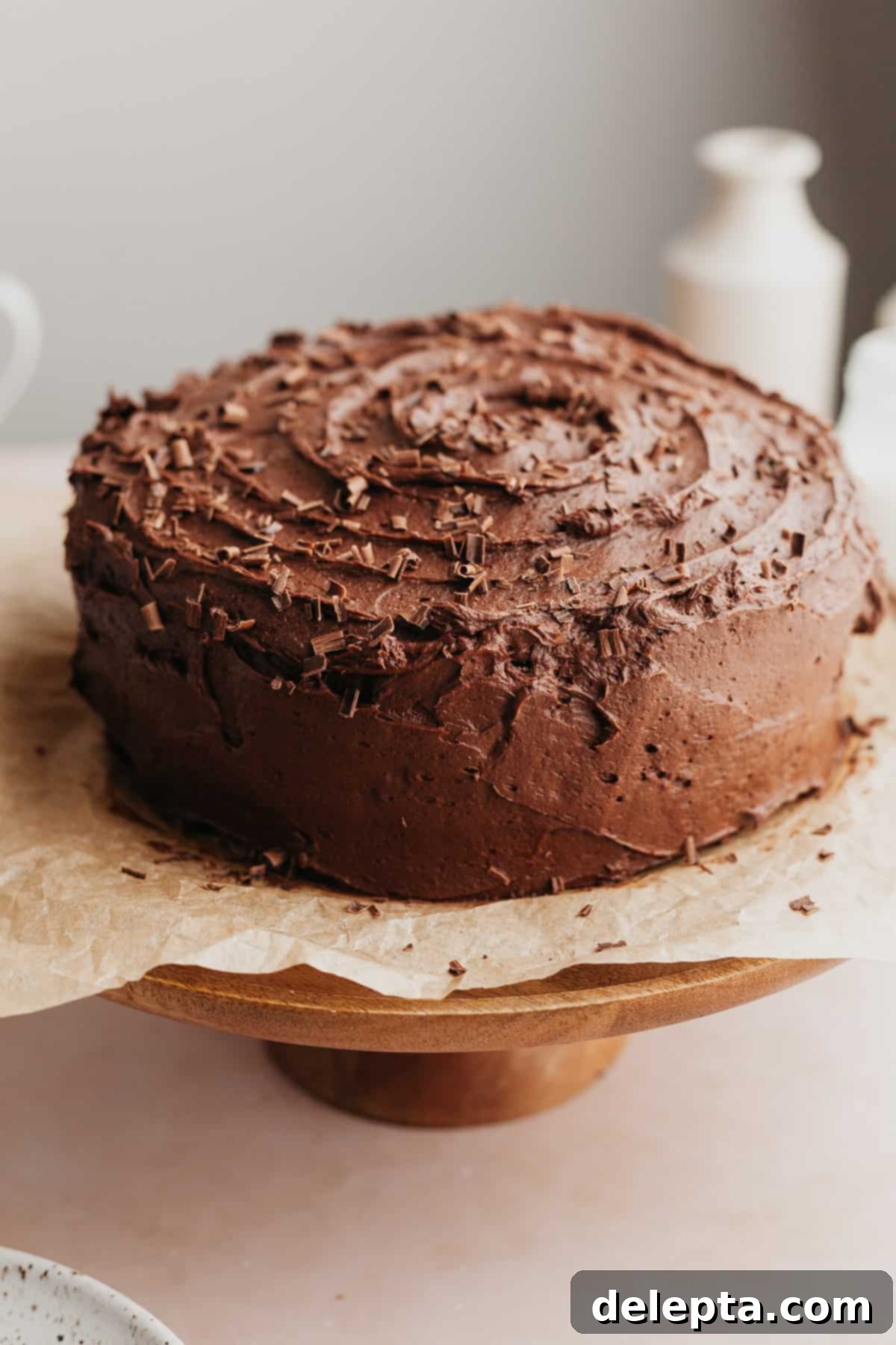 Ultimate Triple Chocolate Indulgence 10 A beautifully frosted triple chocolate layer cake presented on an elegant wooden cake stand, ready to be served and enjoyed.
