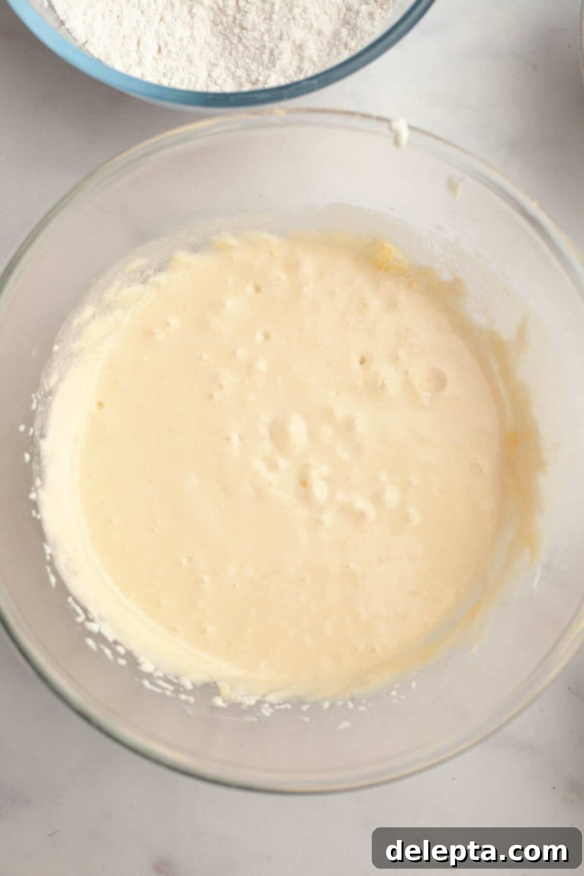 Velvety Vanilla, Chocolate Bliss 5 Creamy, pale yellow cupcake batter being mixed in a large silver stand mixer bowl, showcasing the ideal light and fluffy consistency after creaming butter and sugar.