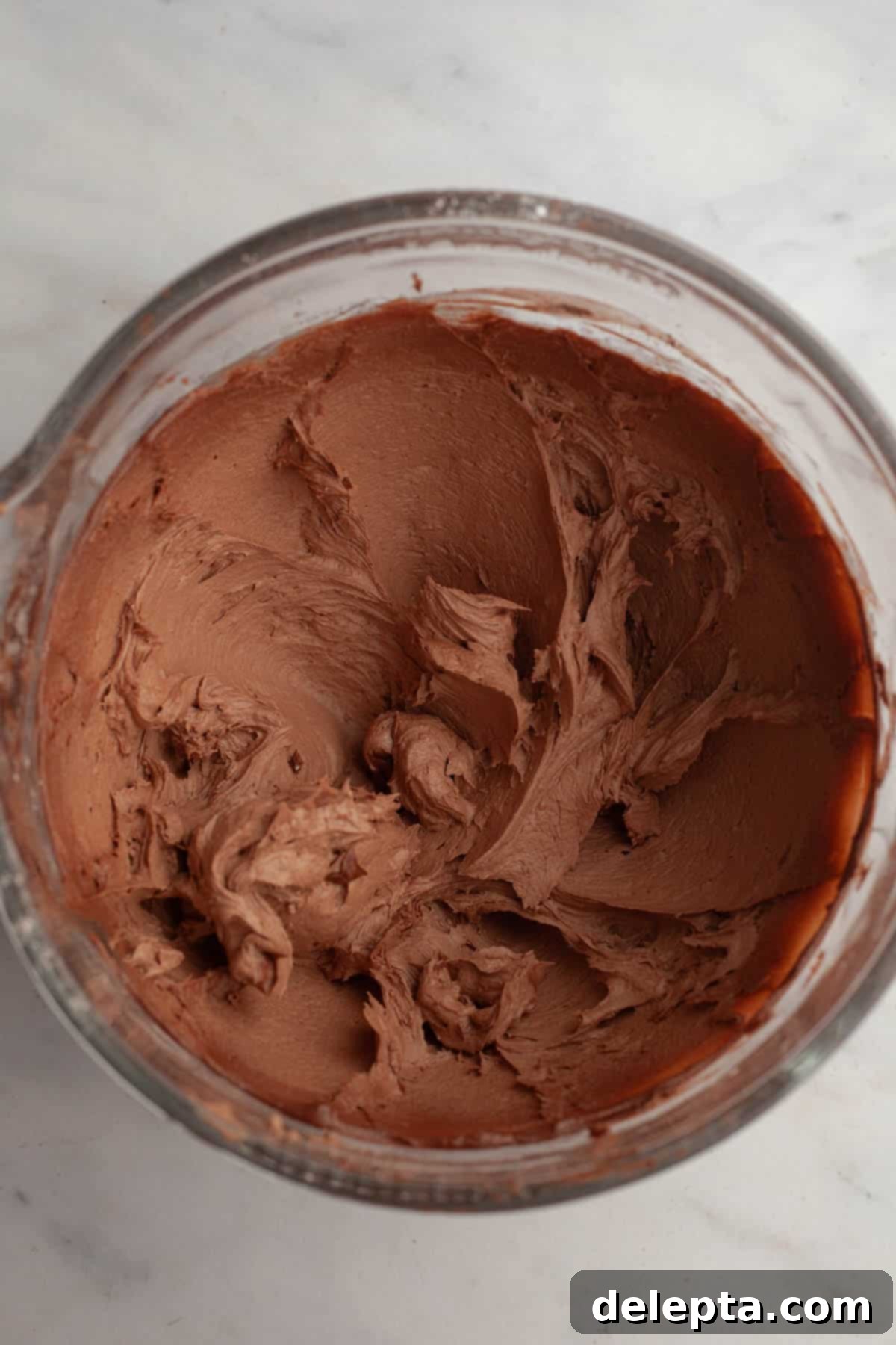Velvety Vanilla, Chocolate Bliss 9 A bowl of freshly made, rich chocolate frosting, smooth and fluffy, ready to be piped onto cooled cupcakes.