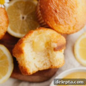 Tangy Lemon Swirl Muffins 8 A close up of a lemon curd muffin with a bite taken out of it.