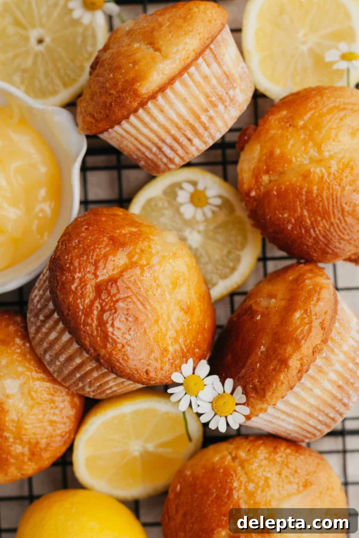 Tangy Lemon Swirl Muffins 6 Freshly baked lemon curd muffins on a wire cooling rack, garnished with lemon slices.