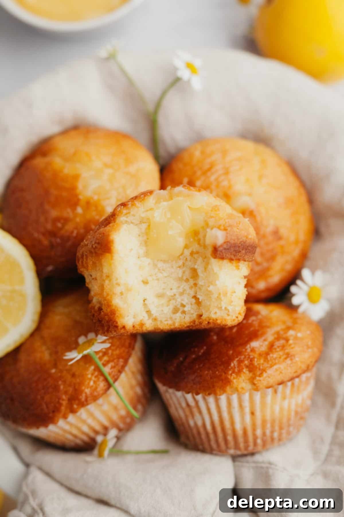 Tangy Lemon Swirl Muffins 7 Lemon curd muffins arranged elegantly on a beige linen.