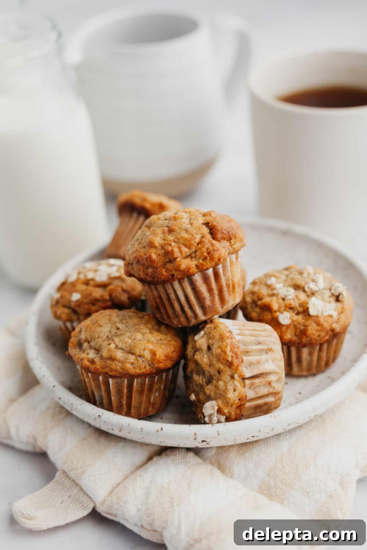 Golden Banana Bites 2 A small plate filled with golden-brown banana mini muffins, garnished with a sprinkle of toasted oats.