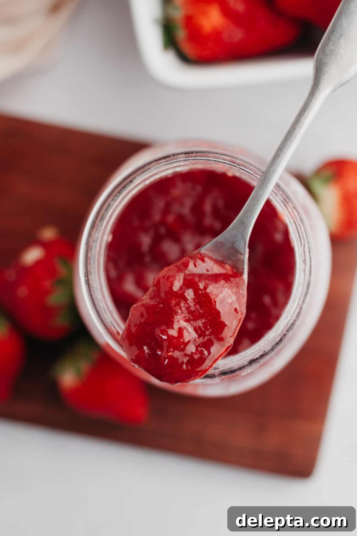 Easy 3 Ingredient Strawberry Cake Filling 2 A spoon with vibrant red homemade strawberry cake filling on it, ready to be enjoyed.