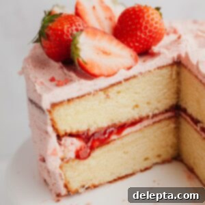 Luscious Vanilla Strawberry Cake 11 A close up of a two layer vanilla cake with a strawberry frosting, the cake has been cut.
