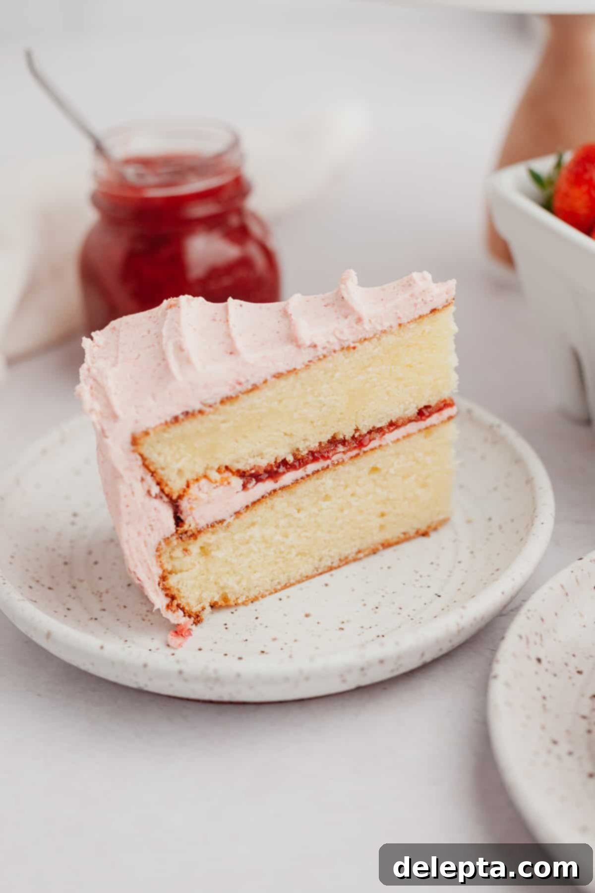 Luscious Vanilla Strawberry Cake 10 A slice of vanilla cake with strawberry filling and frosting.