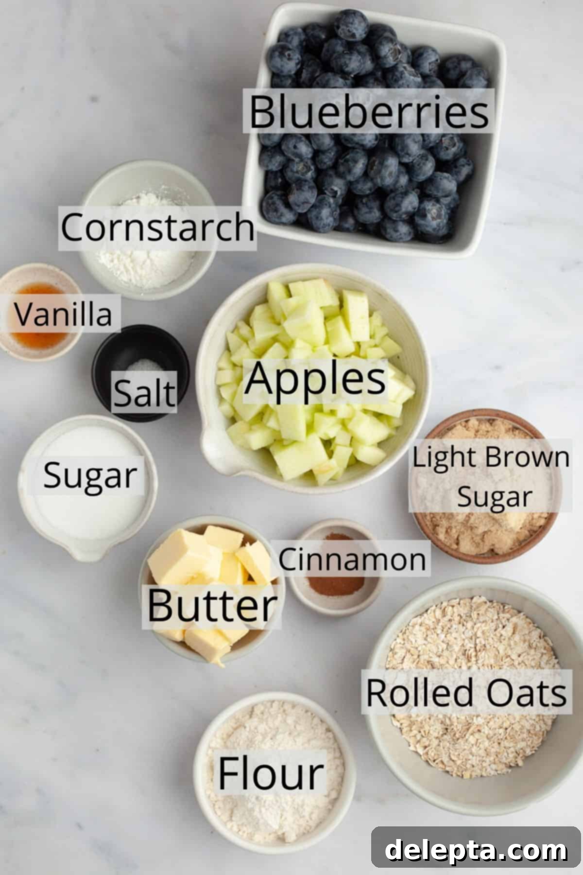 Golden Apple and Berry Crumble 3 Bowls of meticulously measured ingredients for an apple and blueberry crumble, including vibrant fresh blueberries, neatly diced Granny Smith apples, golden rolled oats, all-purpose flour, and various sugars and spices.