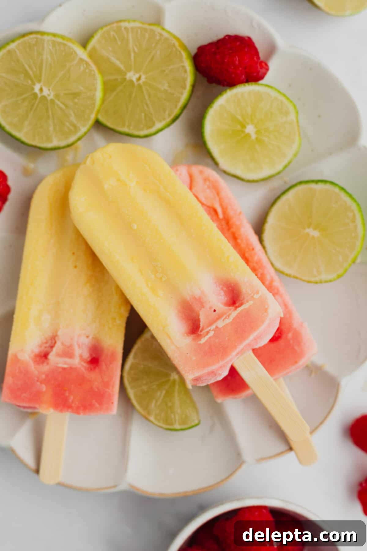 Irresistible Mango Ice Pops 7 Three popsicles that are mango and raspberry flavored.