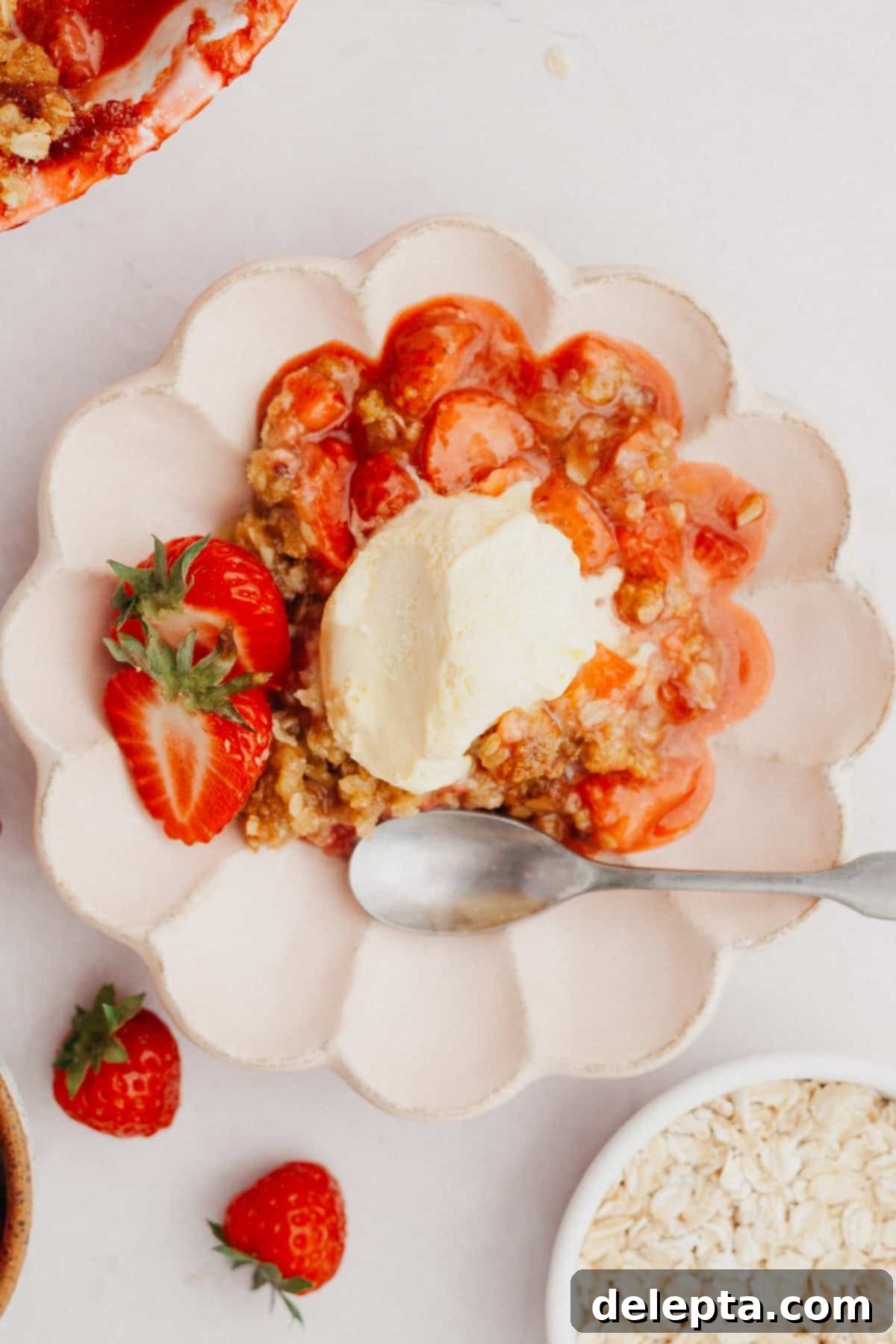 Strawberry Sunshine Crumble 7 A small scalloped white plate holding a serving of warm strawberry crisp, generously topped with a melting scoop of vanilla ice cream.