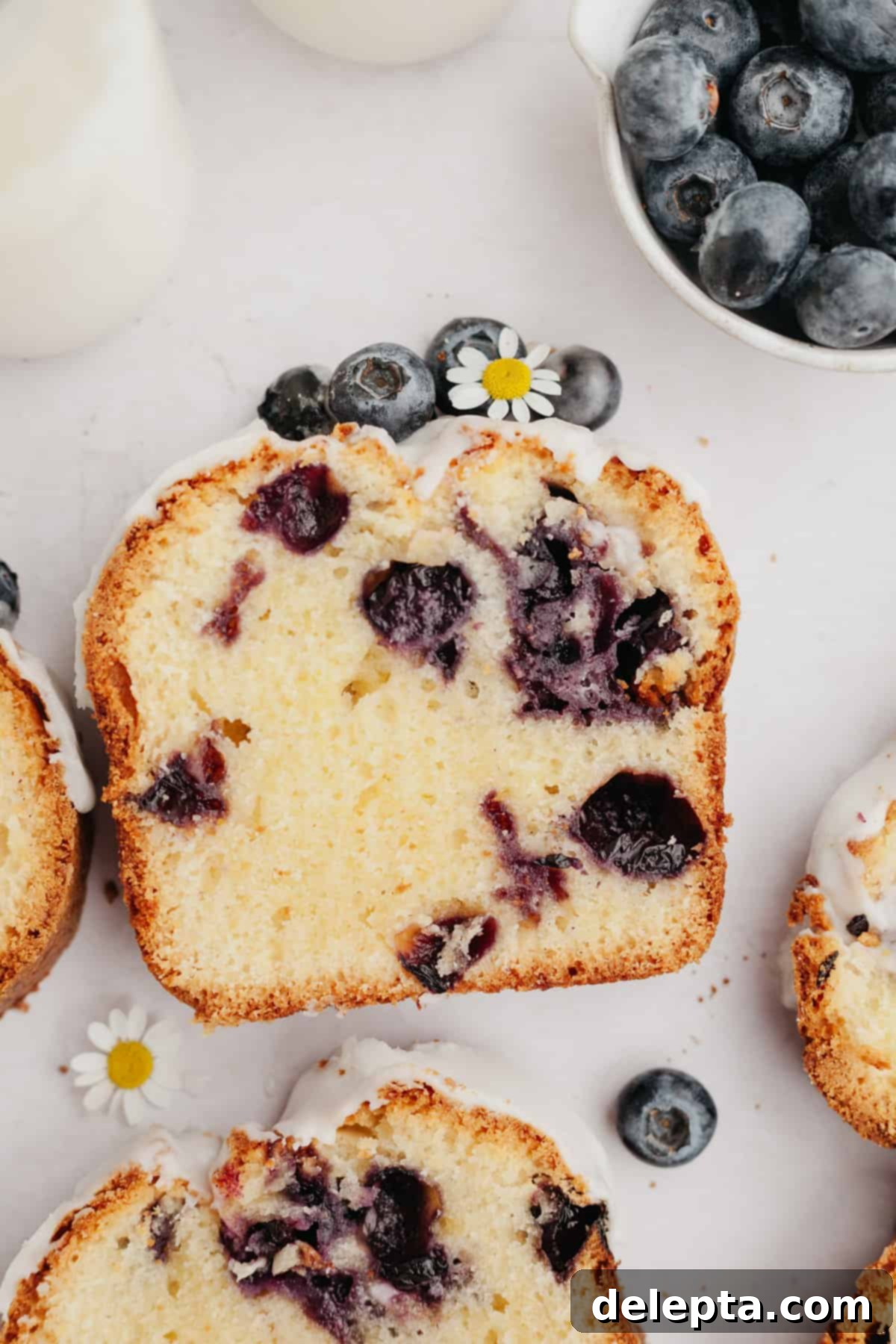 Heavenly Blueberry Pound Cake 7 An overhead shot of a freshly baked slice of blueberry loaf cake with lemon glaze.