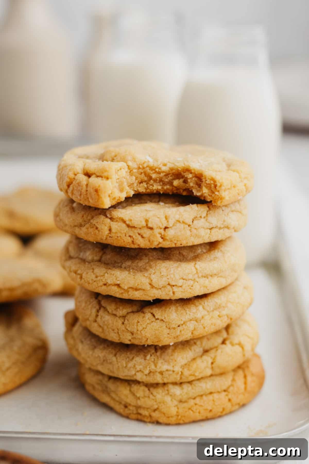 Velvet Chocolate Cookies 7 A perfectly arranged stack of golden chipless cookies on a white baking sheet.