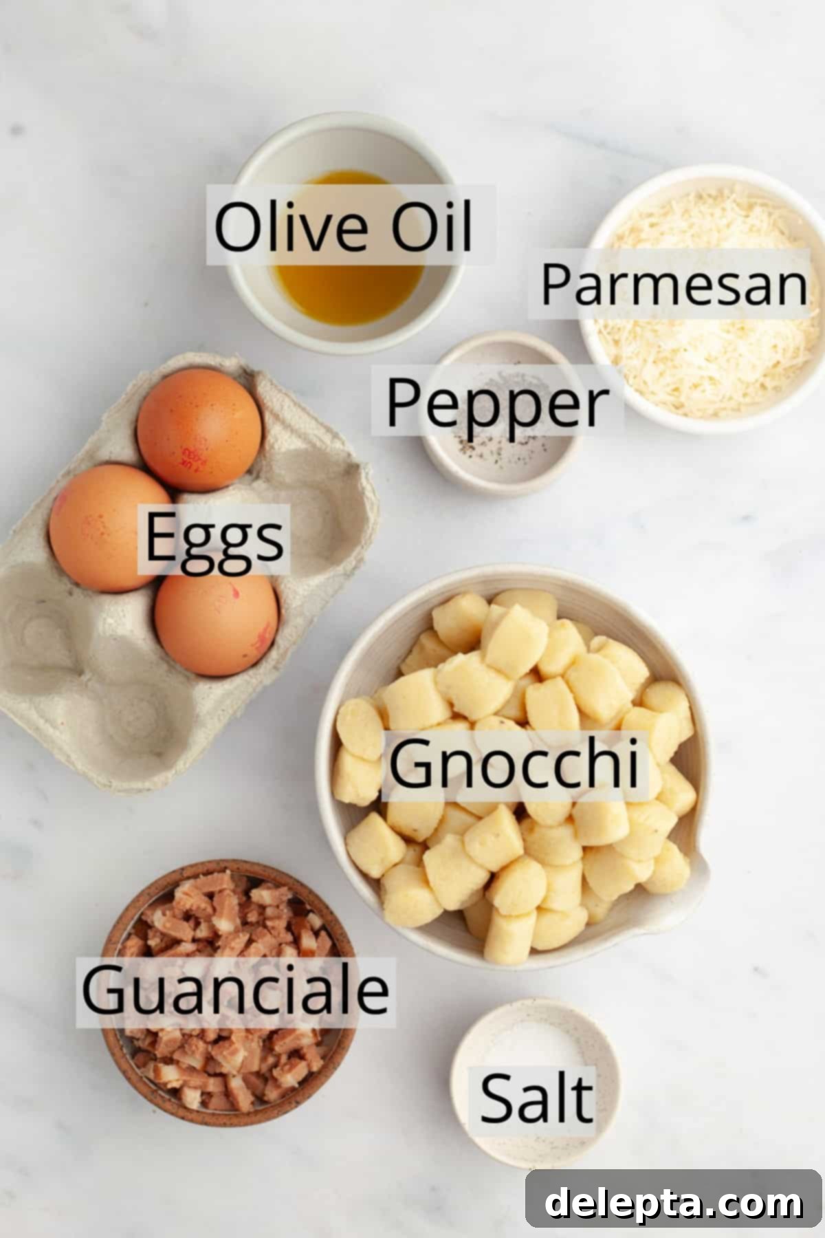 Classic Gnocchi Carbonara 3 All the ingredients needed to make gnocchi carbonara, weighed out into small bowls, including gnocchi, parmesan, eggs, olive oil, and guanciale.