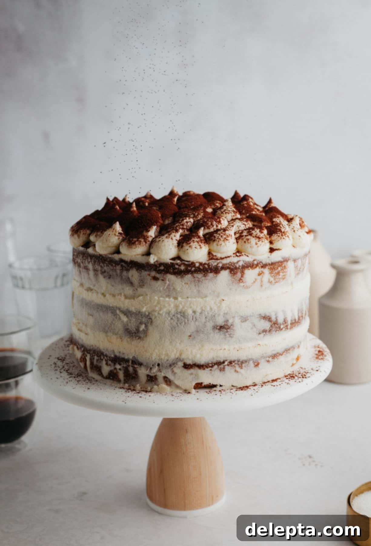 Ultimate Tiramisu Layer Cake 2 A tiramisu layer cake on a white cake stand