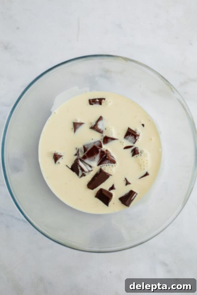 Ultimate Tiramisu Layer Cake 12 A glass bowl with chopped chocolate and heavy cream