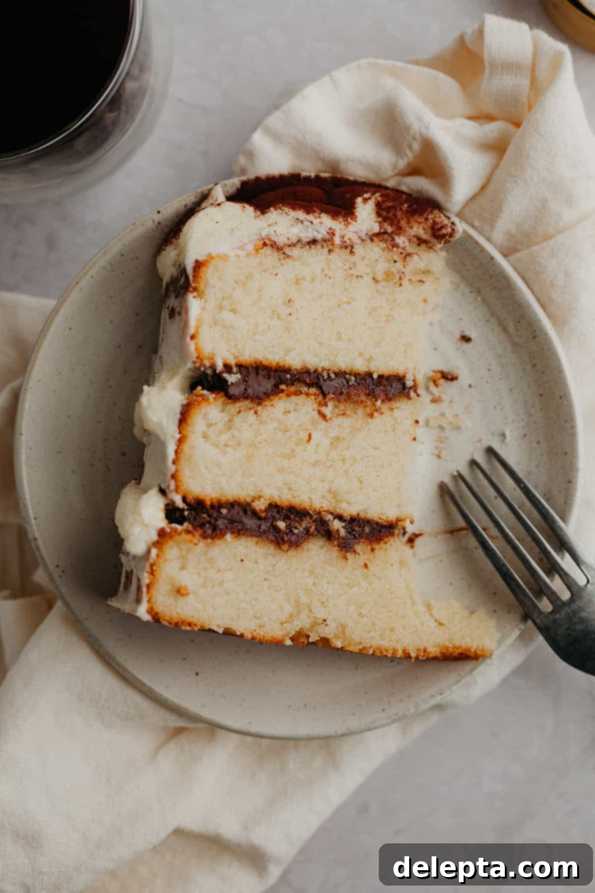 Ultimate Tiramisu Layer Cake 15 A slice of tiramisu cake on a small beige plate