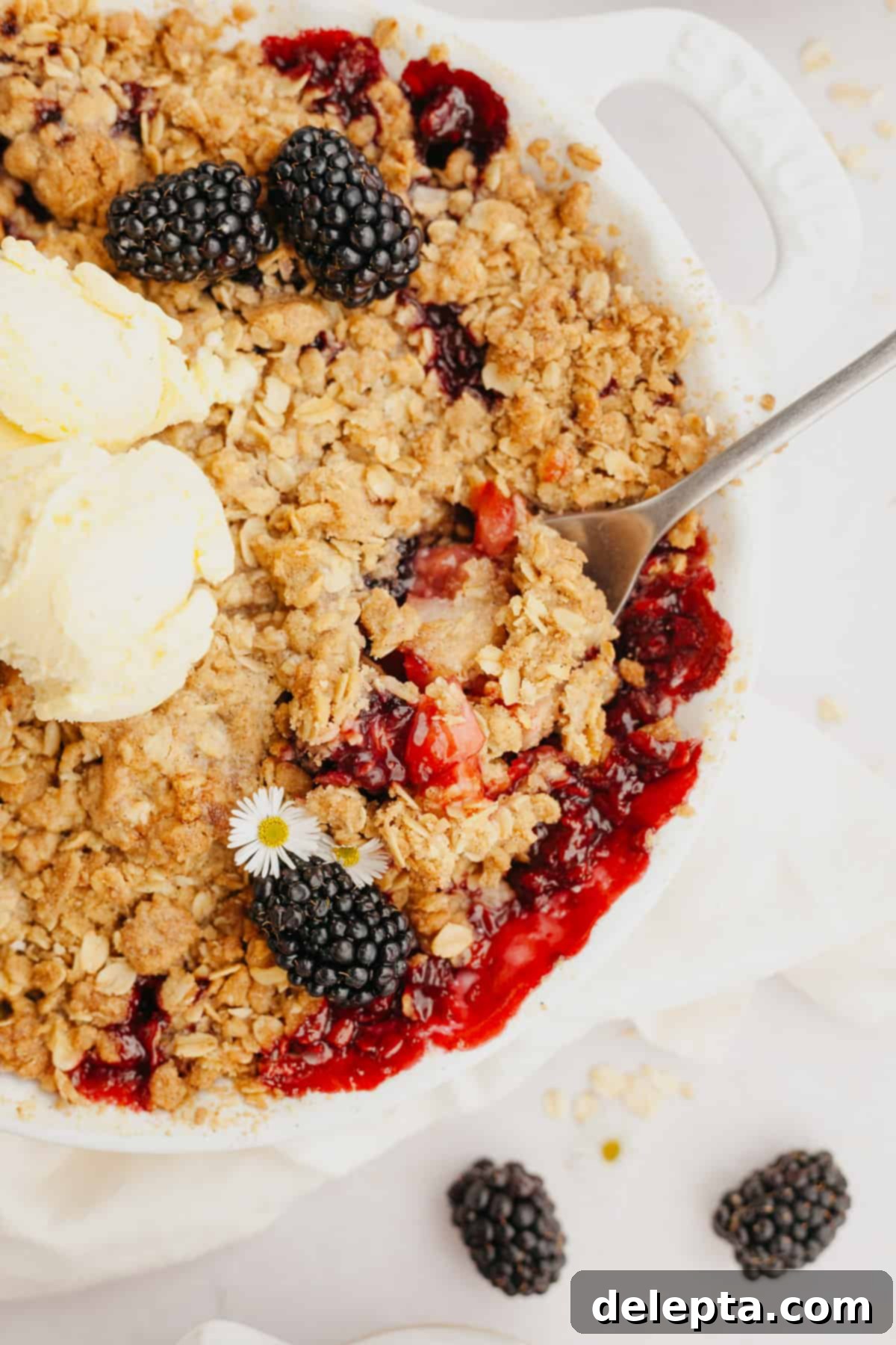 Golden Apple and Blackberry Crumble 6 A close-up shot of the top of a freshly baked blackberry apple crumble, showcasing its golden-brown, crunchy oat streusel topping and bubbling fruit juices.