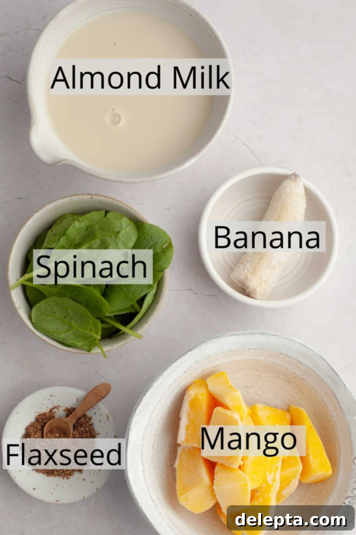 Vibrant Mango Spinach Smoothie 3 All the fresh and frozen ingredients laid out in small bowls, ready for making spinach mango smoothies.