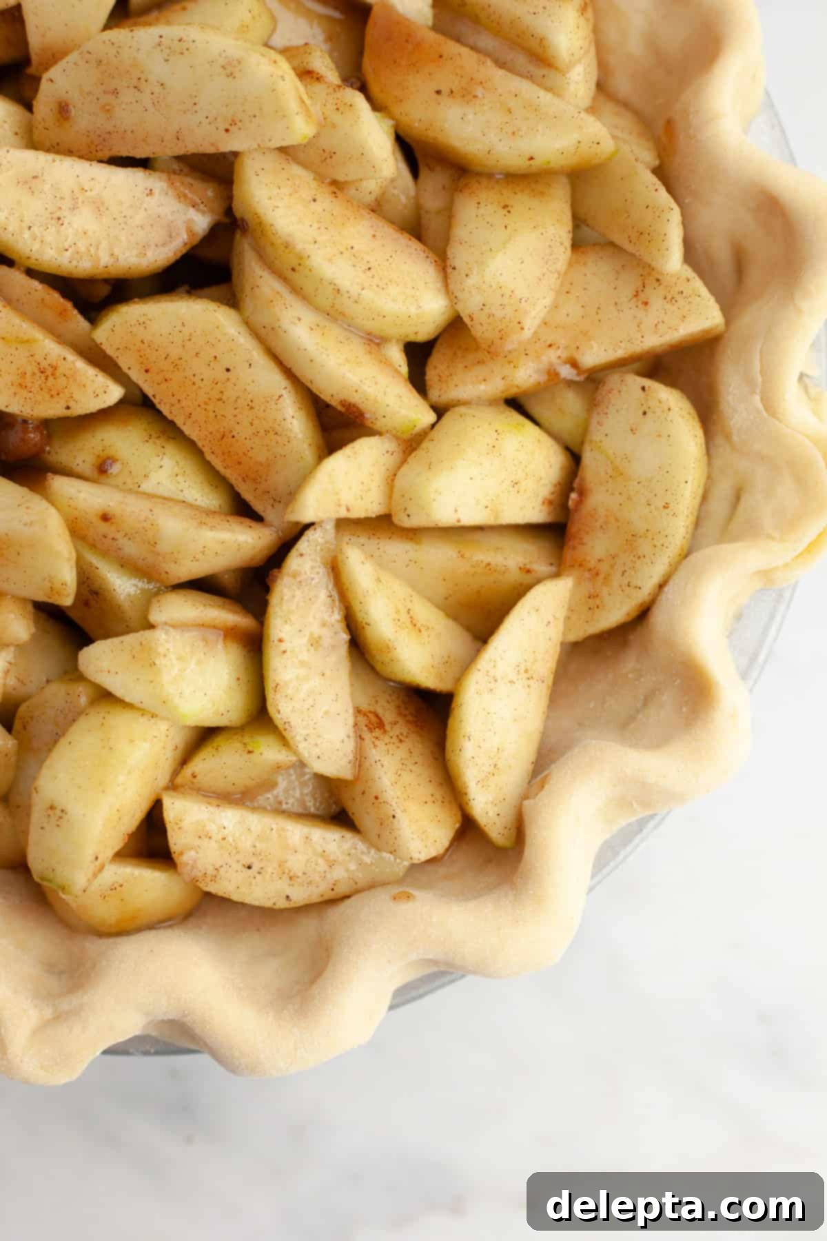 Perfectly Flaky Homemade Pie Crust 9 A crimped pie dough filled with a luscious apple filling, ready for baking.