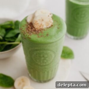 Green Velvet Revitalizer 7 A large glass with a green smoothie in it, it is topped with banana slices.