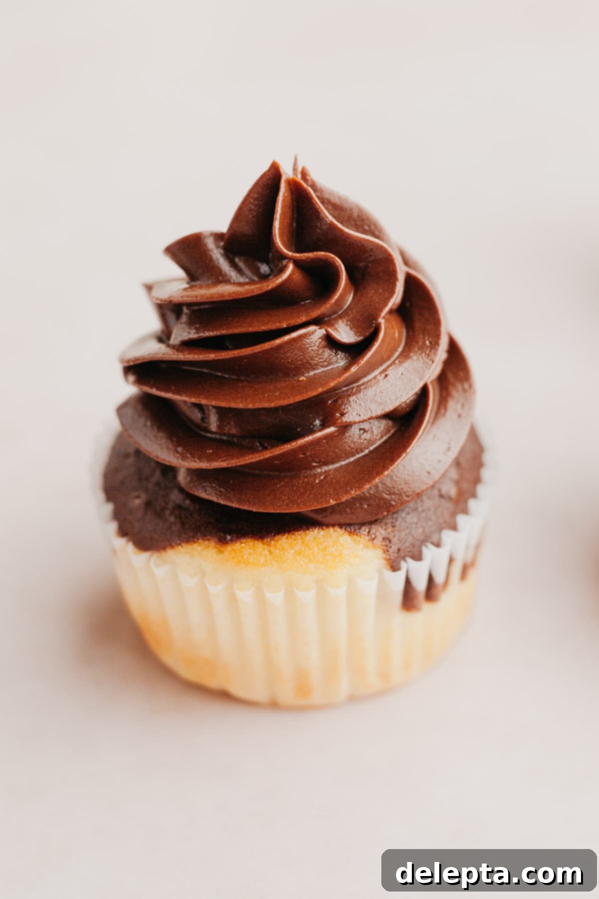 Effortless Whipped Ganache for Bakery-Worthy Cakes 7 A close-up, mouth-watering image of a single cupcake adorned with rich, fluffy chocolate whipped ganache frosting, ready to be enjoyed.