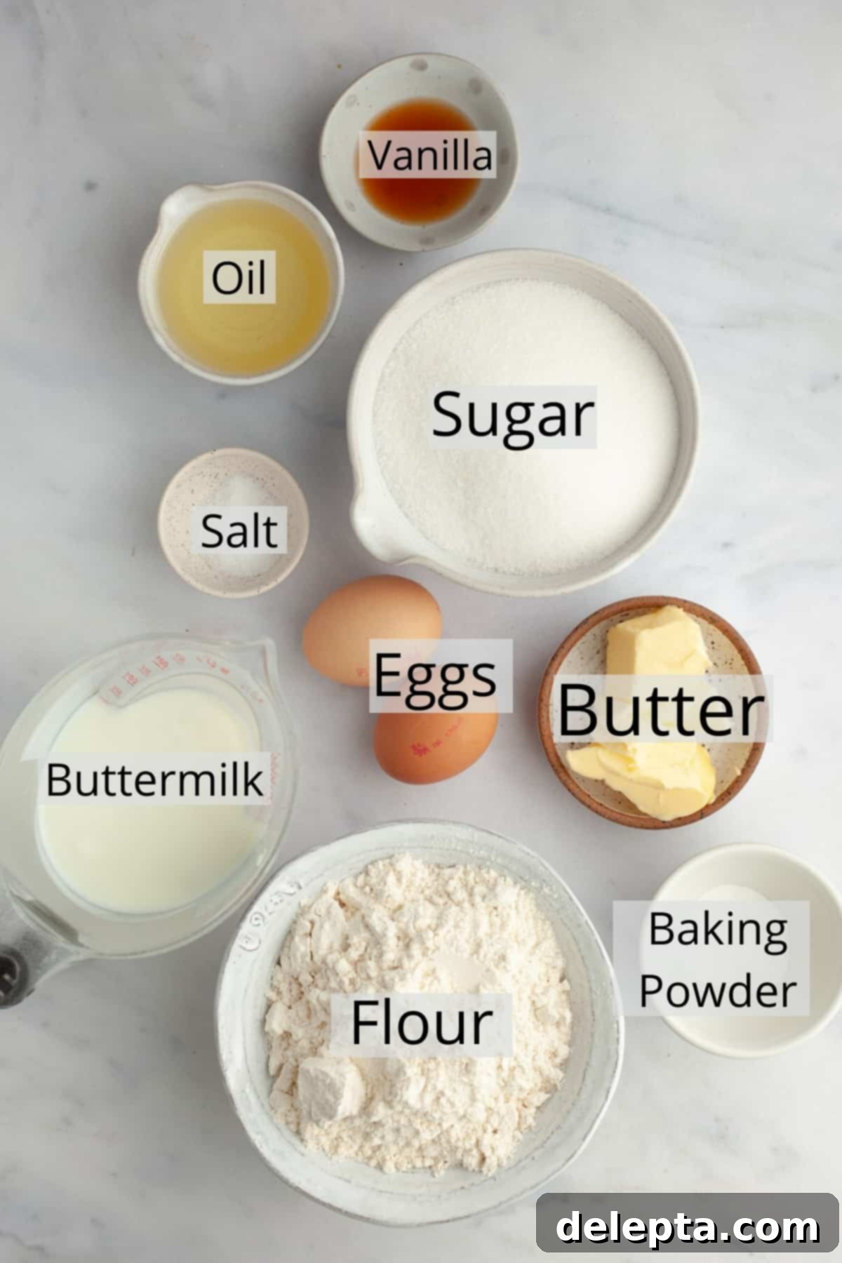 Dainty Vanilla Delights 3 All the pre-measured ingredients required for baking mini vanilla cupcakes are neatly arranged in small bowls on a kitchen counter, ready for mixing.