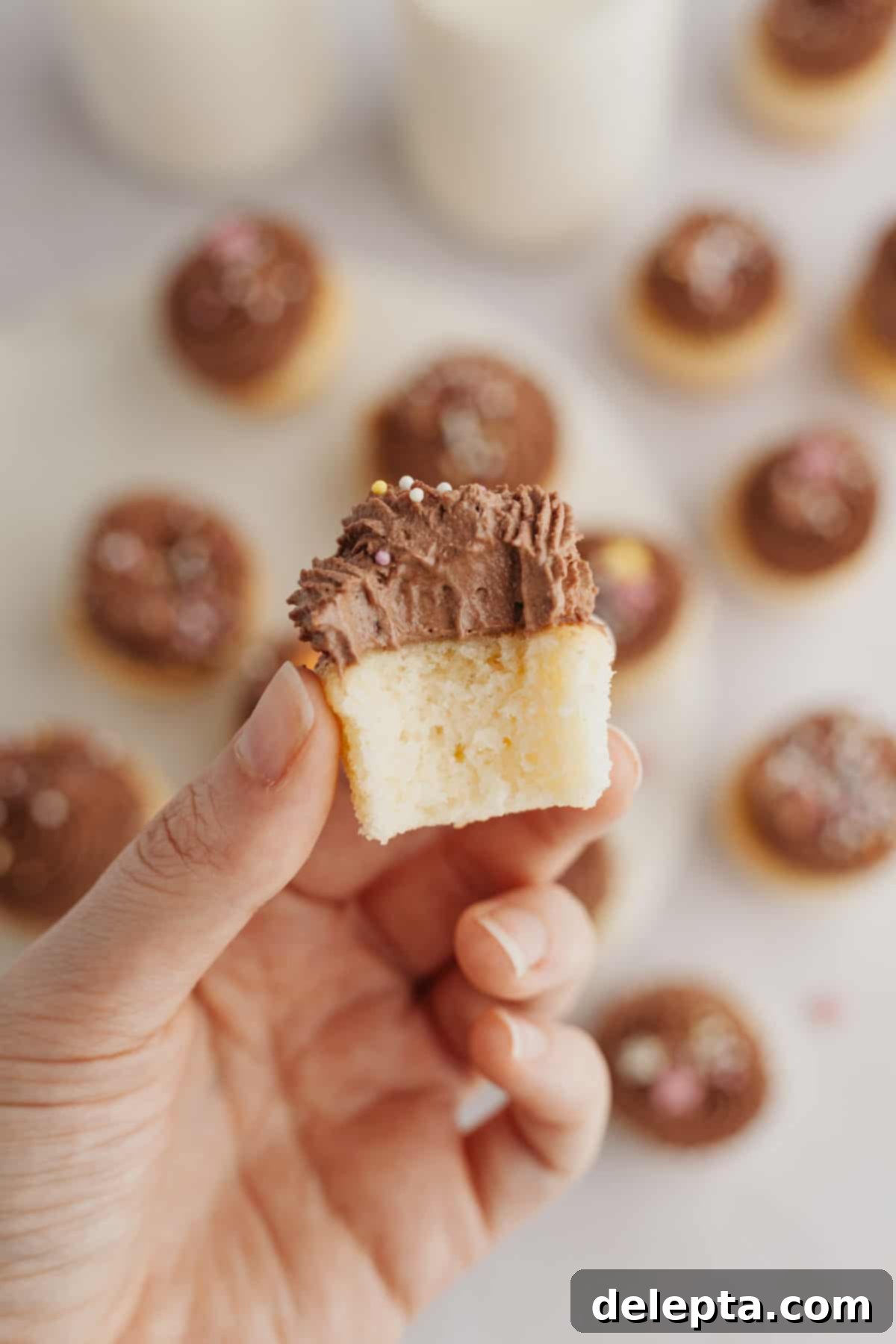 Dreamy Chocolate Cloud Frosting 6 A close up of a mini vanilla cupcake with chocolate frosting, a bite has been taken out of it.