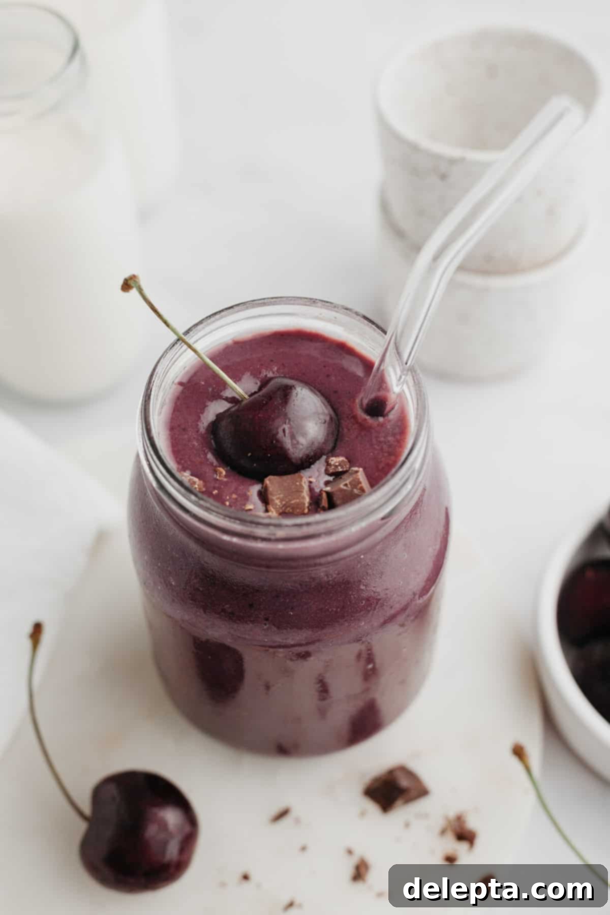 Speedy Chocolate Cherry Indulgence 2 A vibrant chocolate cherry smoothie served in a clear glass jar, garnished with a fresh red cherry on top, highlighting its rich color and appealing texture.