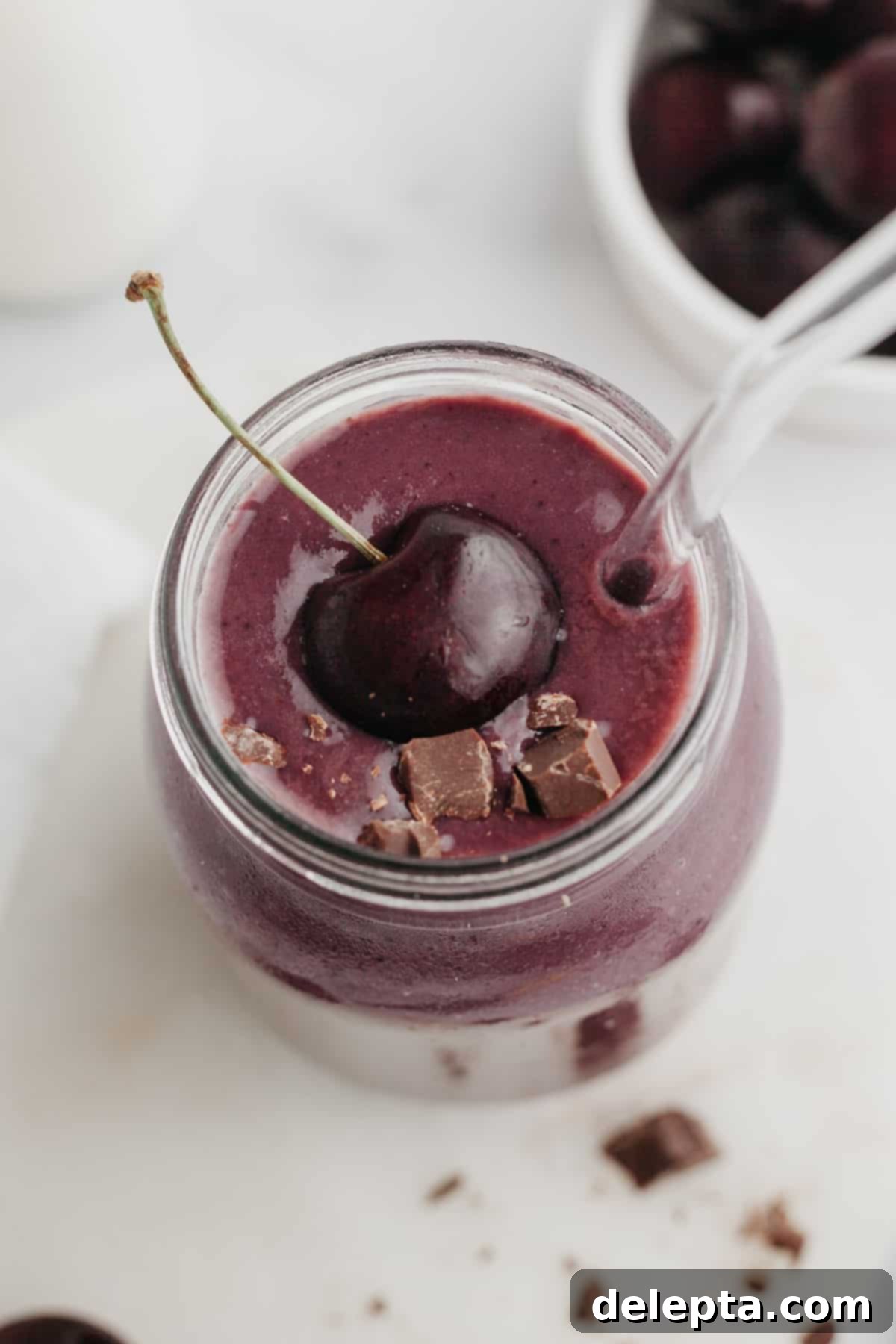 Speedy Chocolate Cherry Indulgence 5 A refreshing chocolate cherry smoothie in a stylish glass jar, artfully garnished with a single fresh cherry, showcasing its appealing color and delicious look.