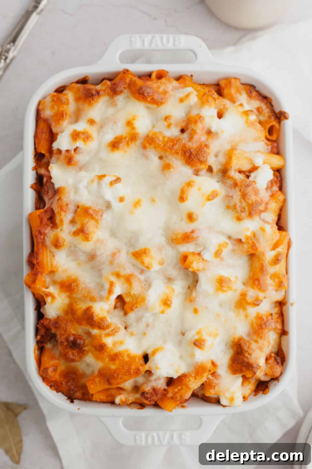 Hearty Three-Cheese Baked Rigatoni with Savory Sausage 2 A white baking dish filled with golden-brown, cheesy baked rigatoni al forno.