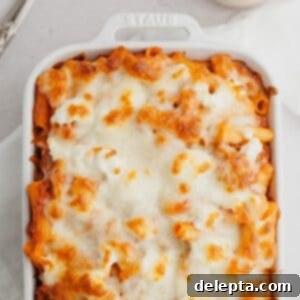 Hearty Three-Cheese Baked Rigatoni with Savory Sausage 9 A white baking dish with a cheesy baked pasta in it.