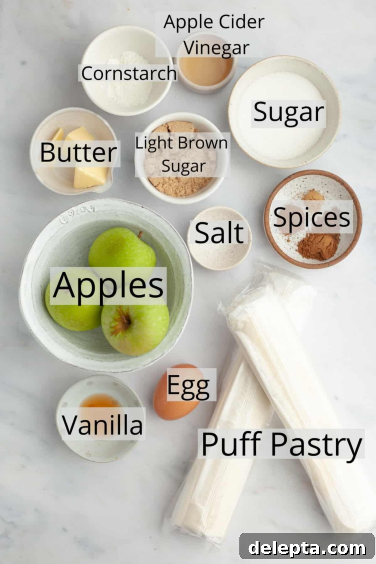 Flaky Apple Puff Pastry Bites 3 All the fresh and pantry ingredients needed to make mini apple pies, neatly arranged in small bowls for clarity.