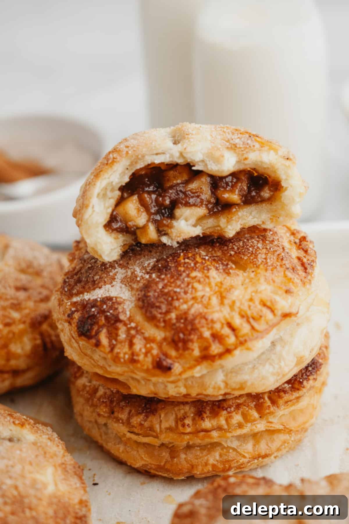 Flaky Apple Puff Pastry Bites 7 A beautifully baked mini apple pie, with golden puff pastry and a visible apple filling, placed on a dark surface.