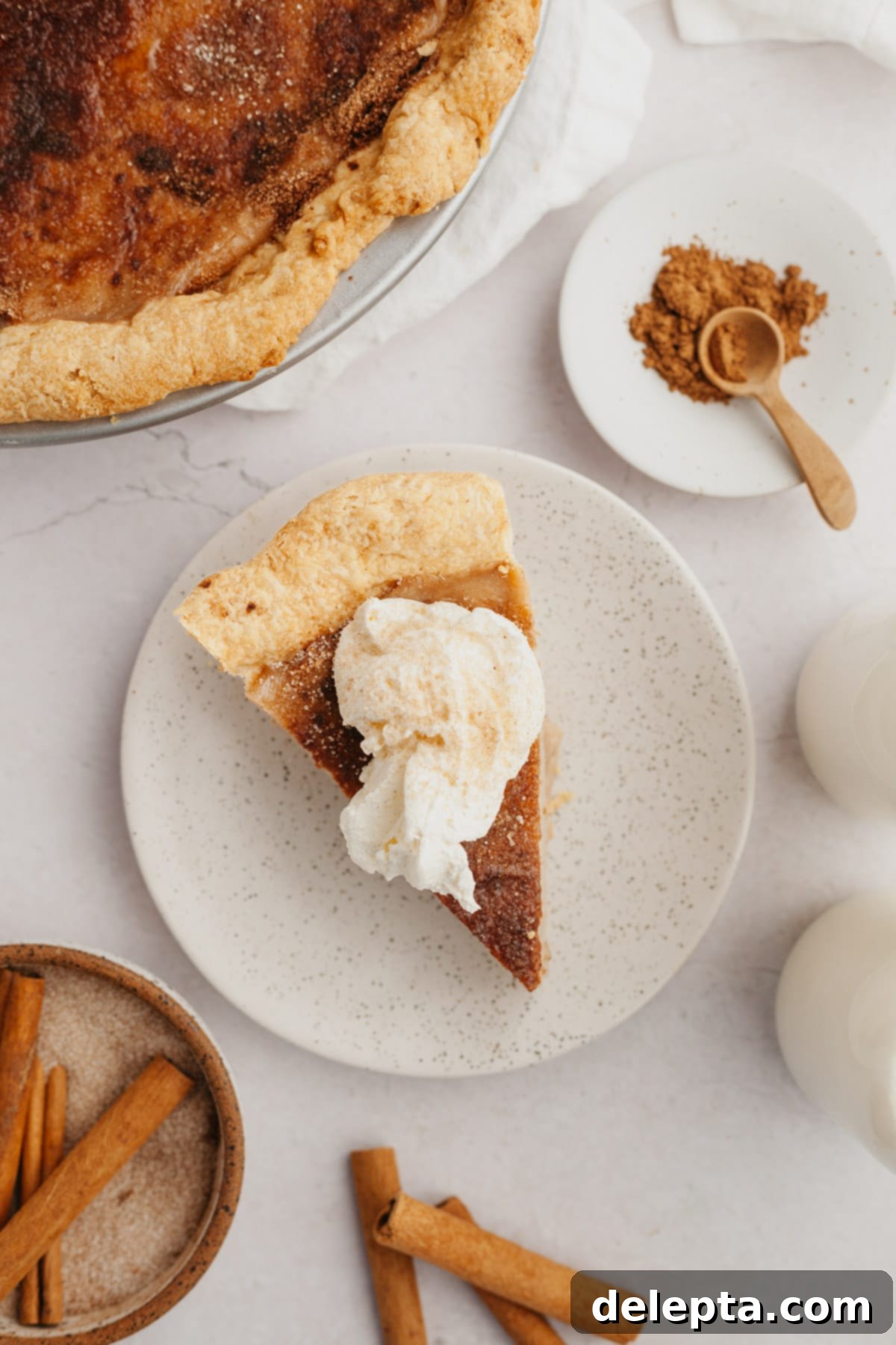 Effortless Cinnamon Pie 7 A slice of pie topped with whipped cream on a small plate.