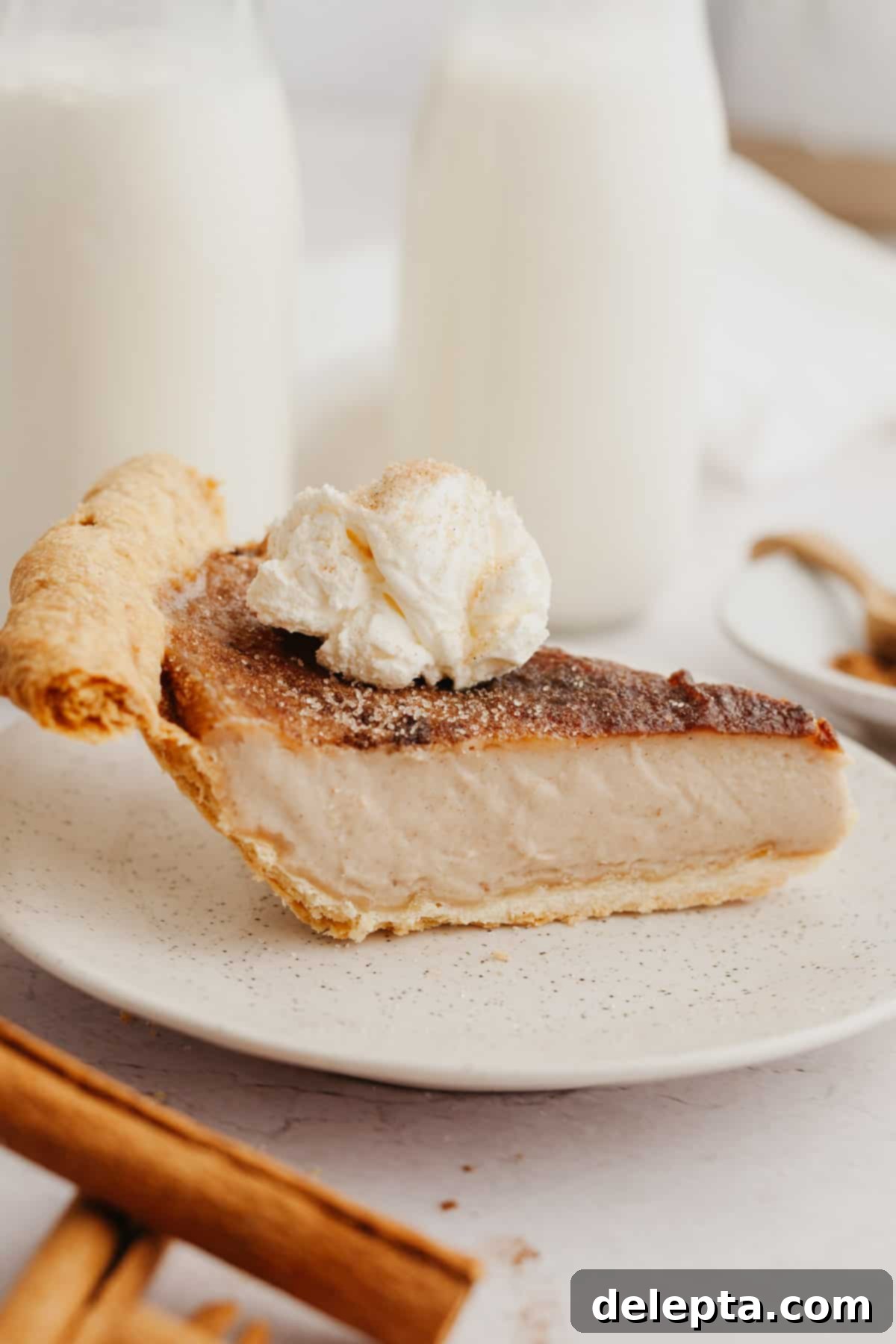 Effortless Cinnamon Pie 8 A slice of pie topped with whipped cream on a small plate.