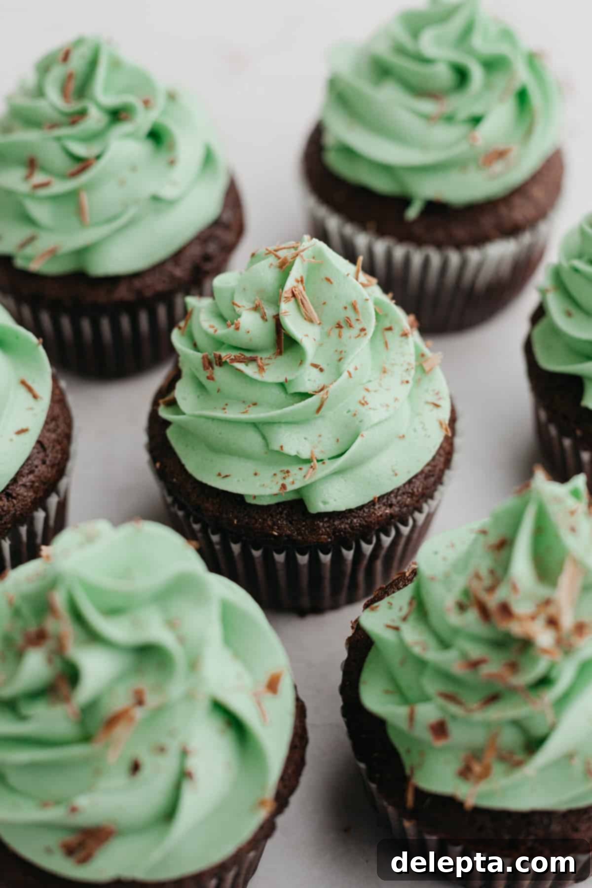 Simple Mint Chocolate Delights 9 Three beautiful mint chocolate cupcakes, adorned with green frosting and chocolate sprinkles, arranged elegantly on a white surface.
