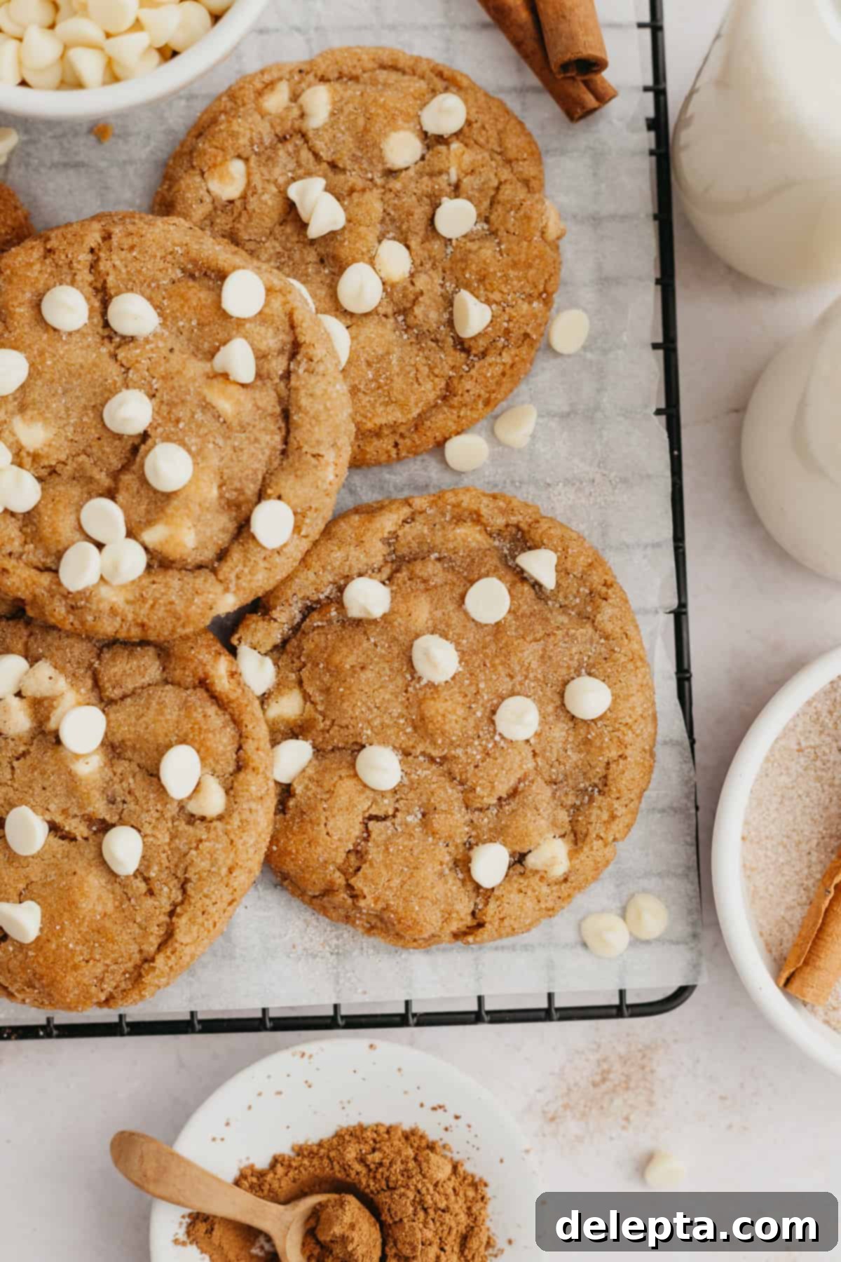 Soft-Baked Pumpkin White Chocolate Chip Delights 2 Pumpkin cookies with white chocolate chips on parchment paper.