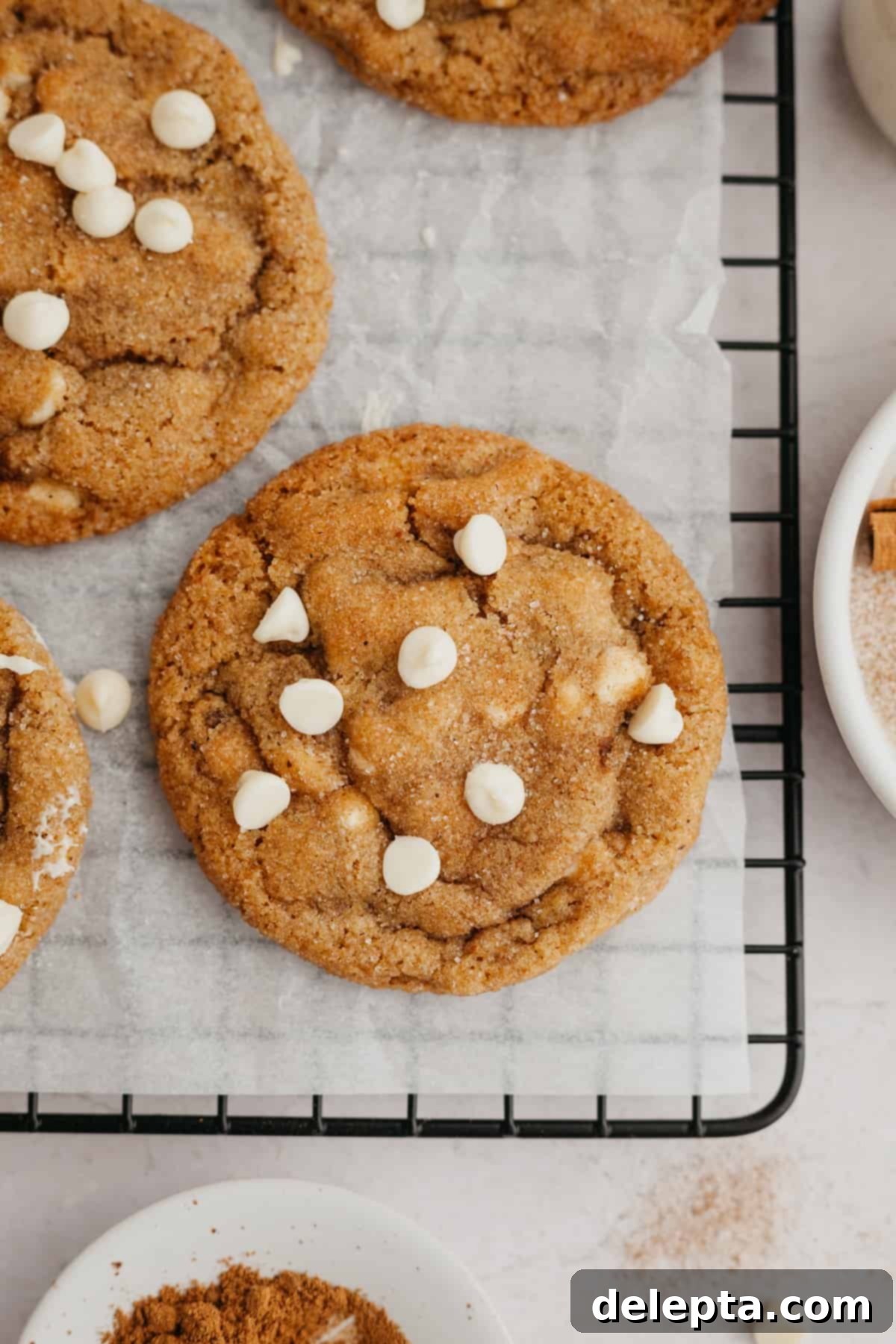 Soft-Baked Pumpkin White Chocolate Chip Delights 8 Pumpkin cookies with white chocolate chips on parchment paper.