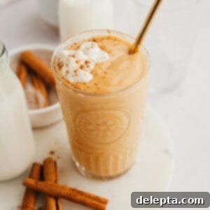 Creamy Banana Pumpkin Pie Smoothie 7 A perfectly blended, creamy pumpkin pie smoothie in a tall glass, garnished with a sprinkle of spice, showcasing its inviting autumnal color.