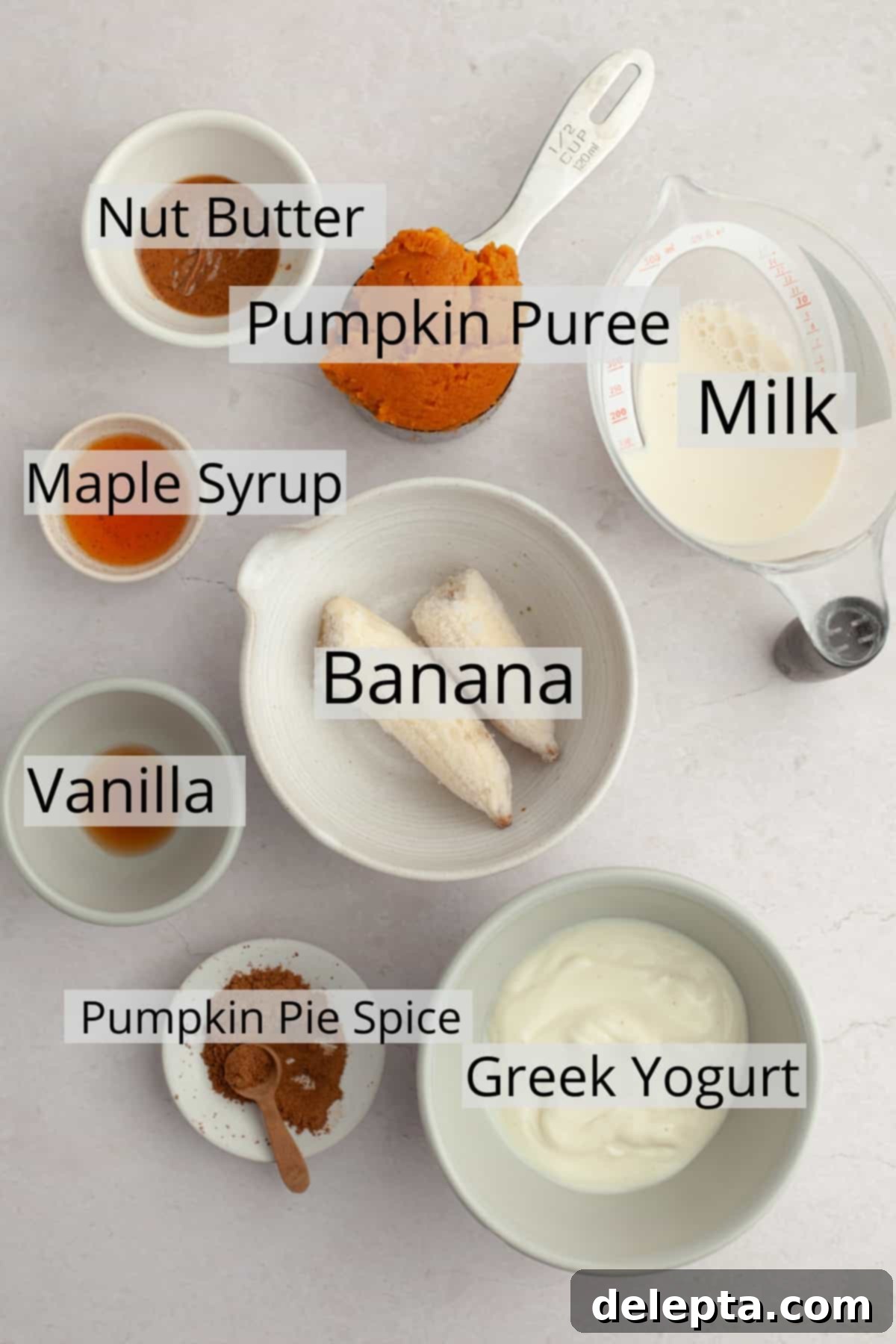 Creamy Banana Pumpkin Pie Smoothie 3 Various healthy pumpkin smoothie ingredients, including pumpkin puree, frozen banana slices, Greek yogurt, and spices, neatly arranged in small bowls for a clear ingredient shot.
