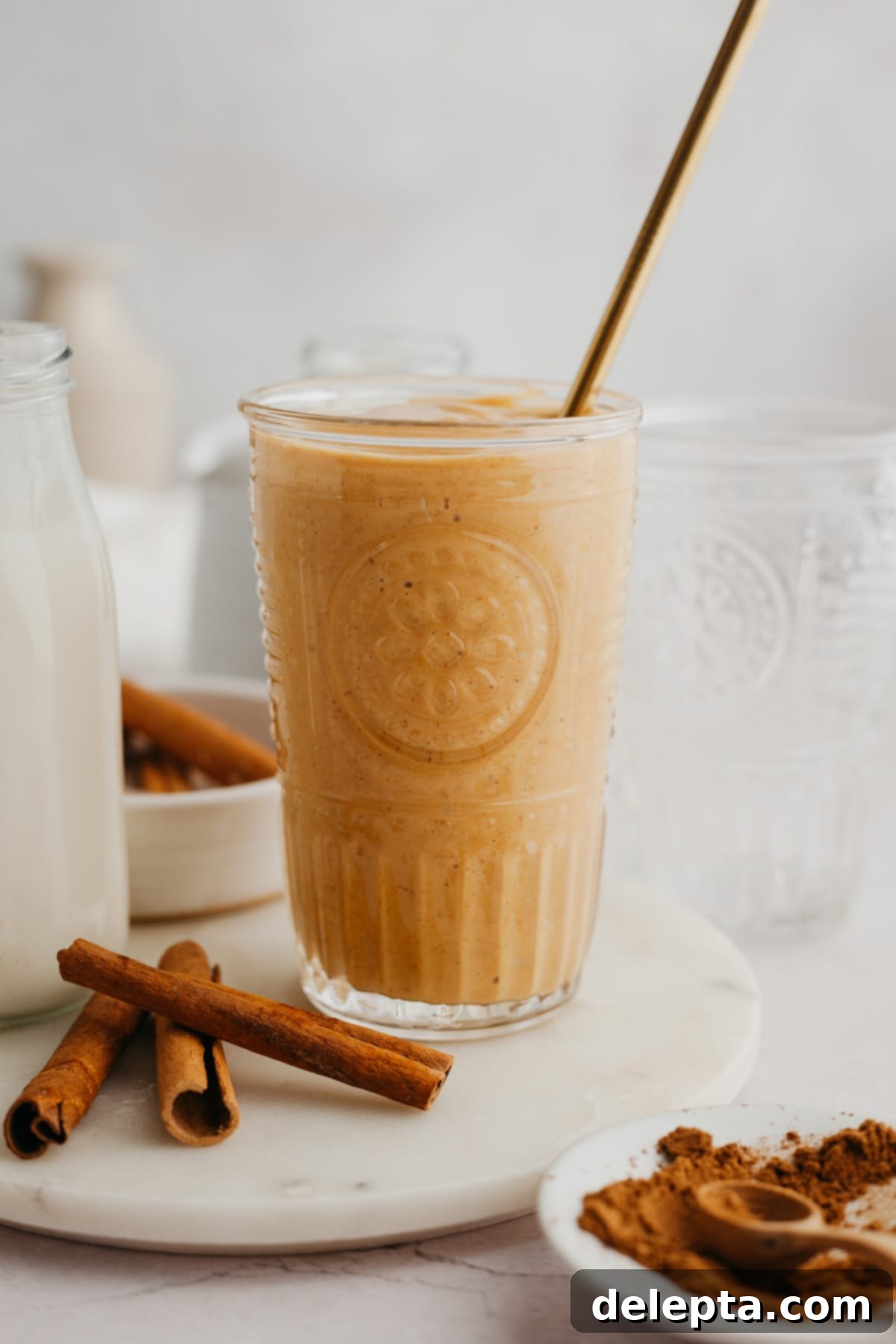 Creamy Banana Pumpkin Pie Smoothie 6 A beautifully textured pumpkin smoothie in a tall glass, highlighted with ambient lighting, ready to be enjoyed as a perfect fall refreshment.