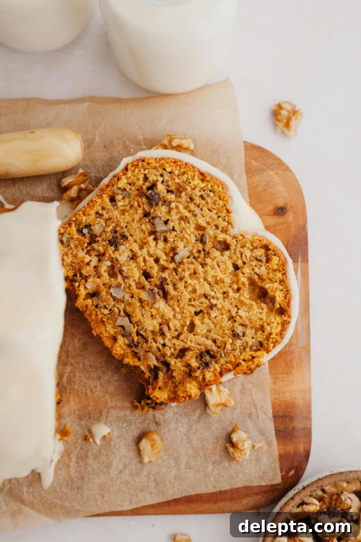 Spiced Pumpkin Walnut Loaf with Maple Glaze 2 A beautifully glazed slice of moist pumpkin walnut bread on a wooden cutting board, ready to be enjoyed.