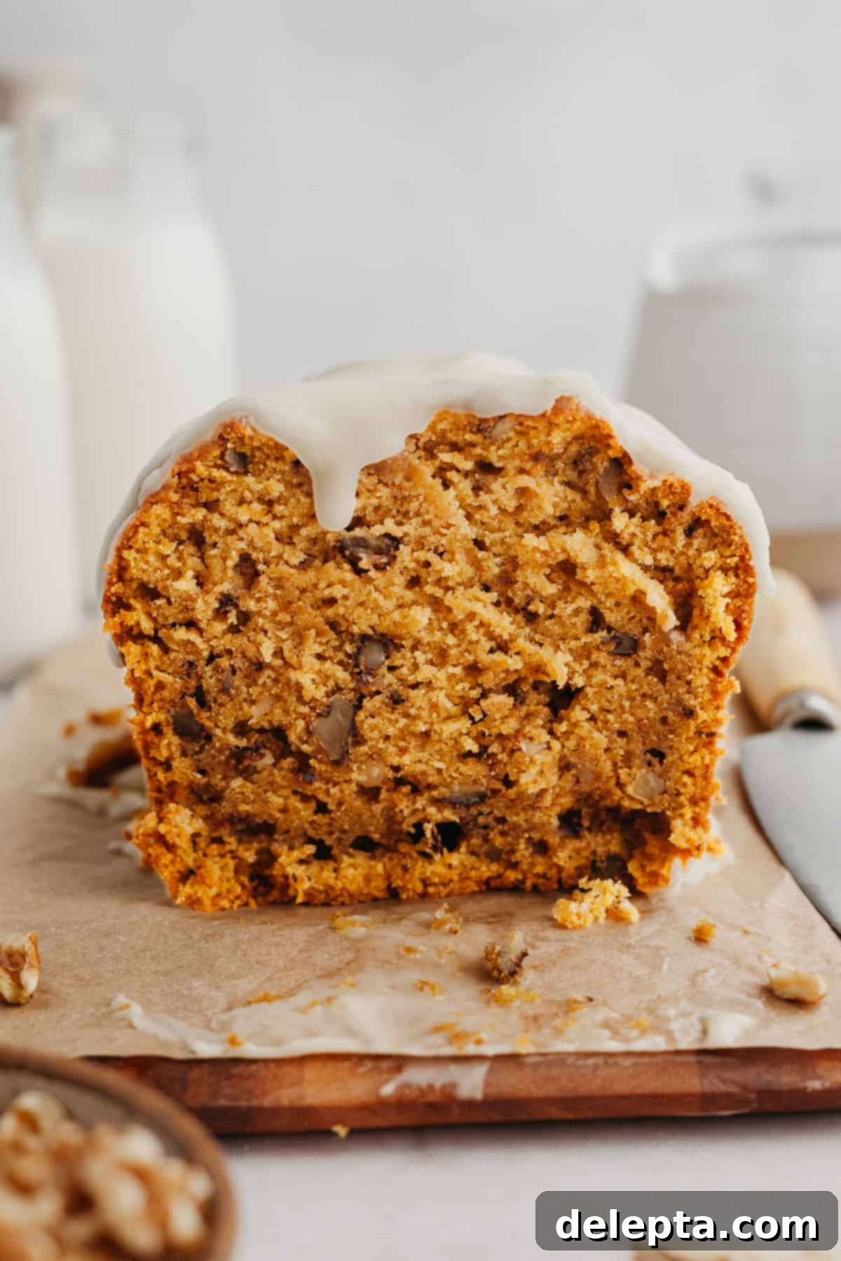 Spiced Pumpkin Walnut Loaf with Maple Glaze 7 A whole pumpkin loaf with maple glaze, resting on a wooden cutting board.