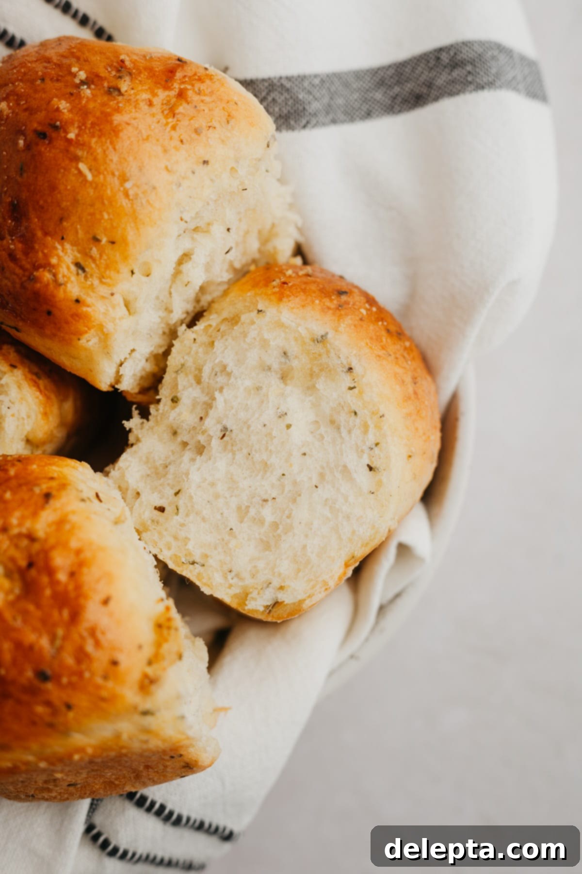 Irresistibly Soft and Fluffy Garlic Dinner Rolls 2 Freshly baked garlic dinner rolls, brushed with herb butter and sprinkled with flaky sea salt, cooling in a white baking dish.