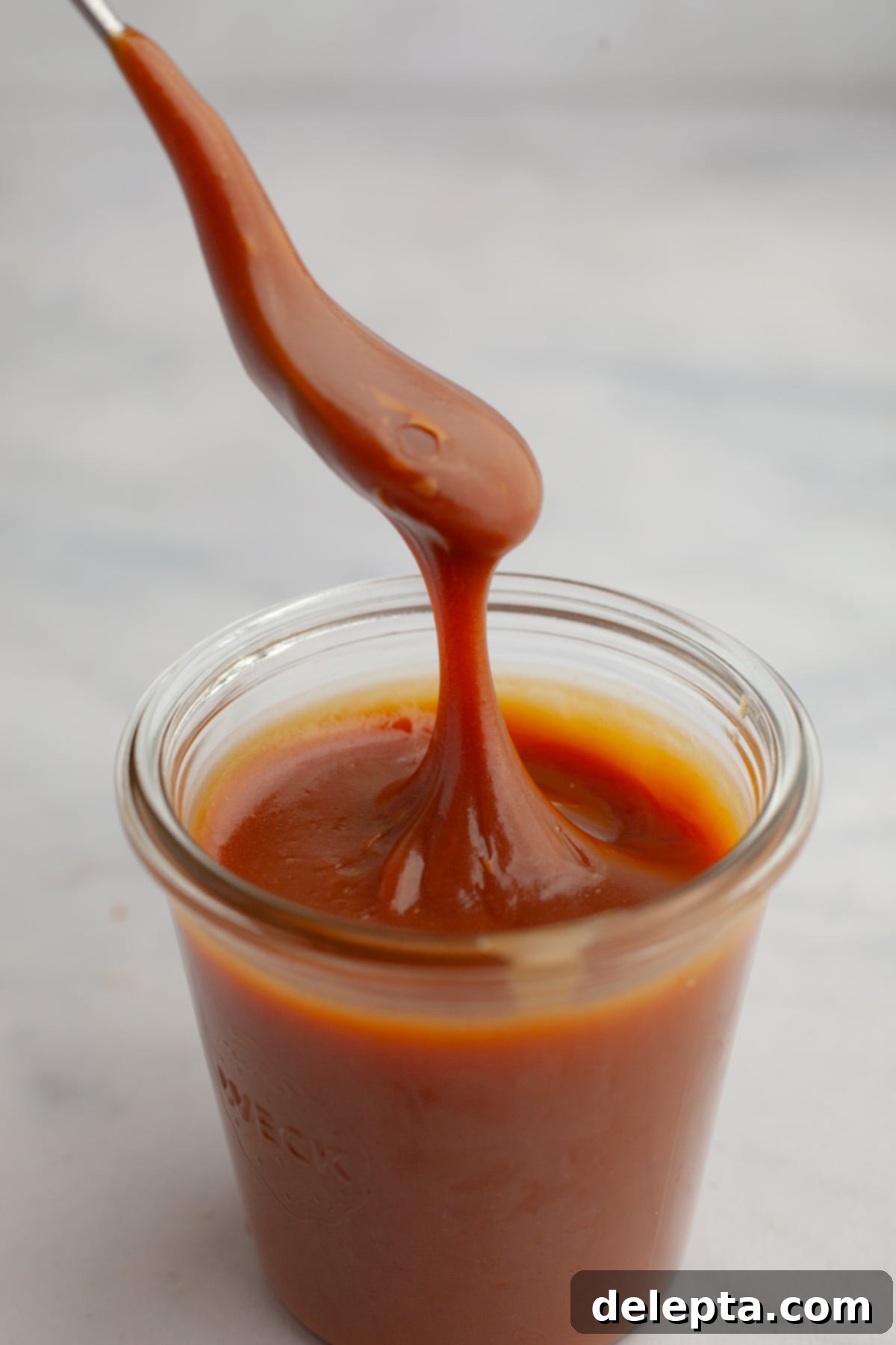 Decadent Homemade Salted Caramel Sauce 2 A beautiful jar of golden salted caramel sauce with a spoon resting in it, ready to be enjoyed.