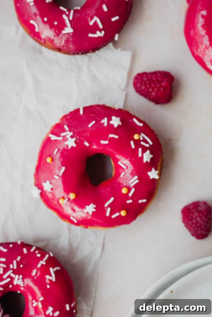 Vanilla Dream Doughnuts with a Raspberry Kiss 6 Overhead view of a pink doughnut with white sprinkles