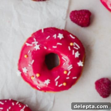 Vanilla Dream Doughnuts with a Raspberry Kiss 8 Overhead view of a pink doughnut with white sprinkles