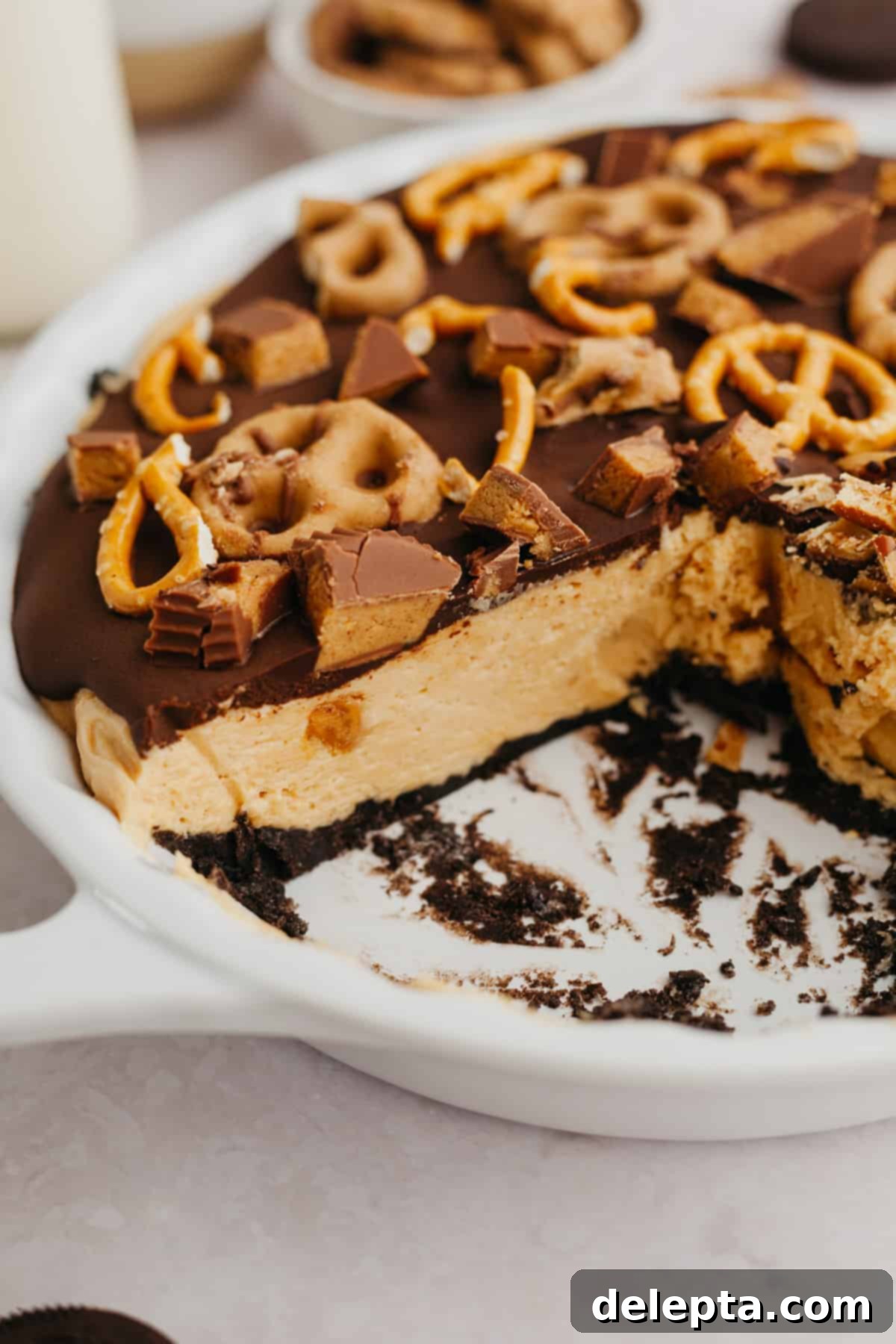 Decadent No-Bake Oreo Peanut Butter Pie 2 A perfectly sliced Oreo peanut butter pie in a white serving dish, revealing its distinct layers of dark Oreo crust, light peanut butter filling, and glistening chocolate ganache.